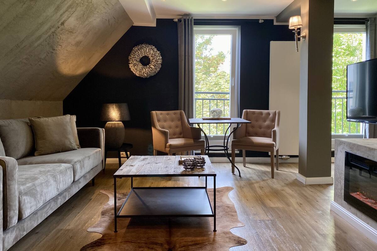 A modern living room with a sofa, two armchairs, a coffee table, and a fireplace.