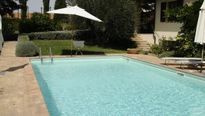 Piscina retangular com água cristalina, rodeada por um pátio de tijolos.
