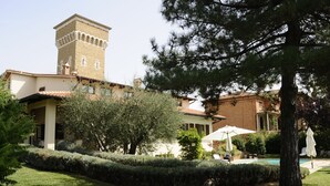 Uma vila com uma torre, piscina e um jardim bem cuidado.