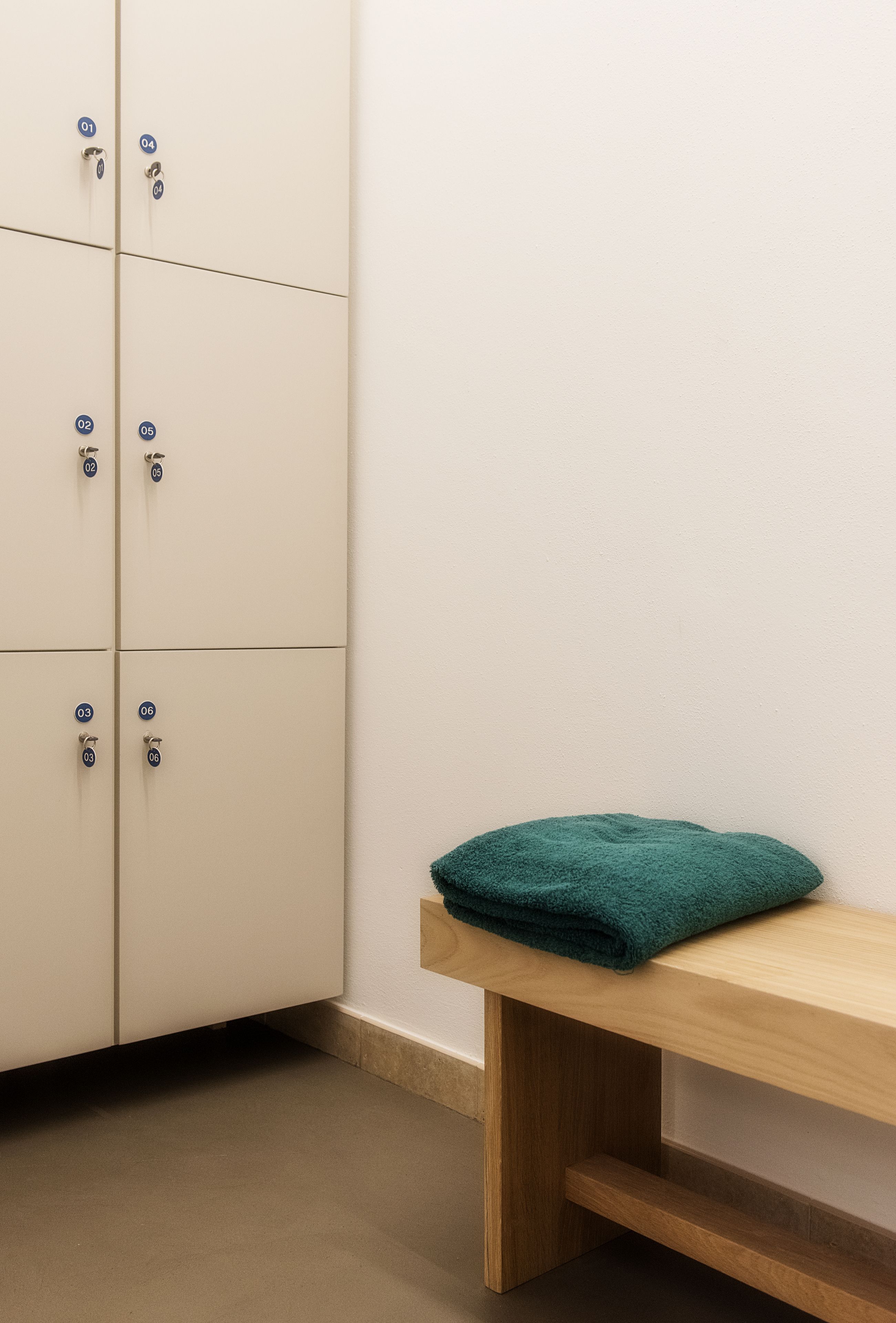 Un coin de pièce avec une armoire blanche et un banc en bois sur lequel est posée une serviette verte.