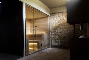 A modern interior with a stone wall, wooden paneling, and a television. - Hotel Rutiliano Centro Benessere (Pienza)