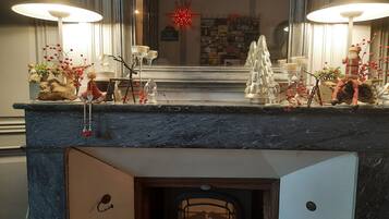 A fireplace with a mantel decorated with various ornaments and a Christmas tree.