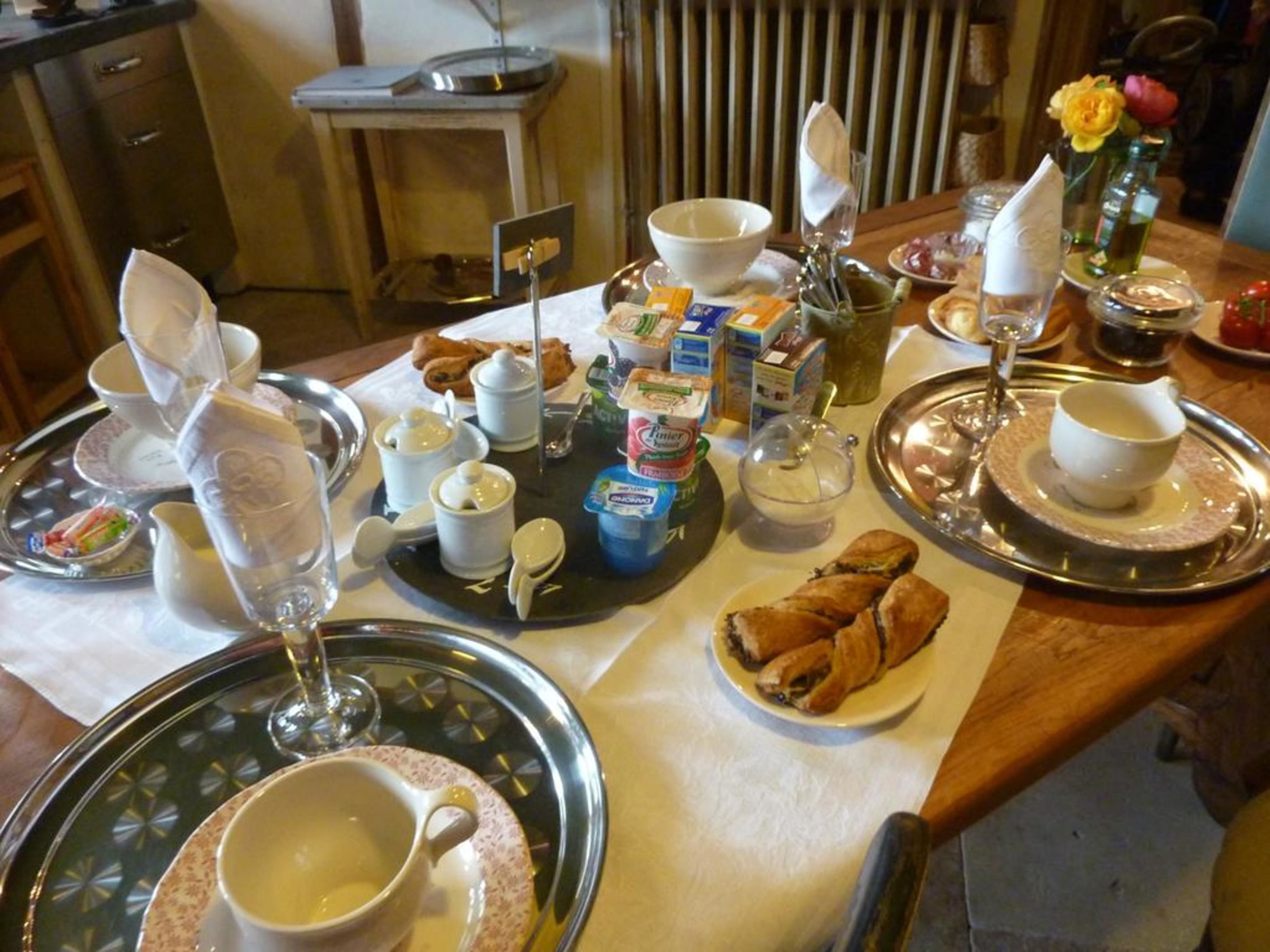 A breakfast table with various food items, including pastries, a croissant, and a glass of juice.