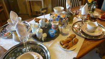 A breakfast table with various food items, including pastries, a croissant, and a glass of juice.