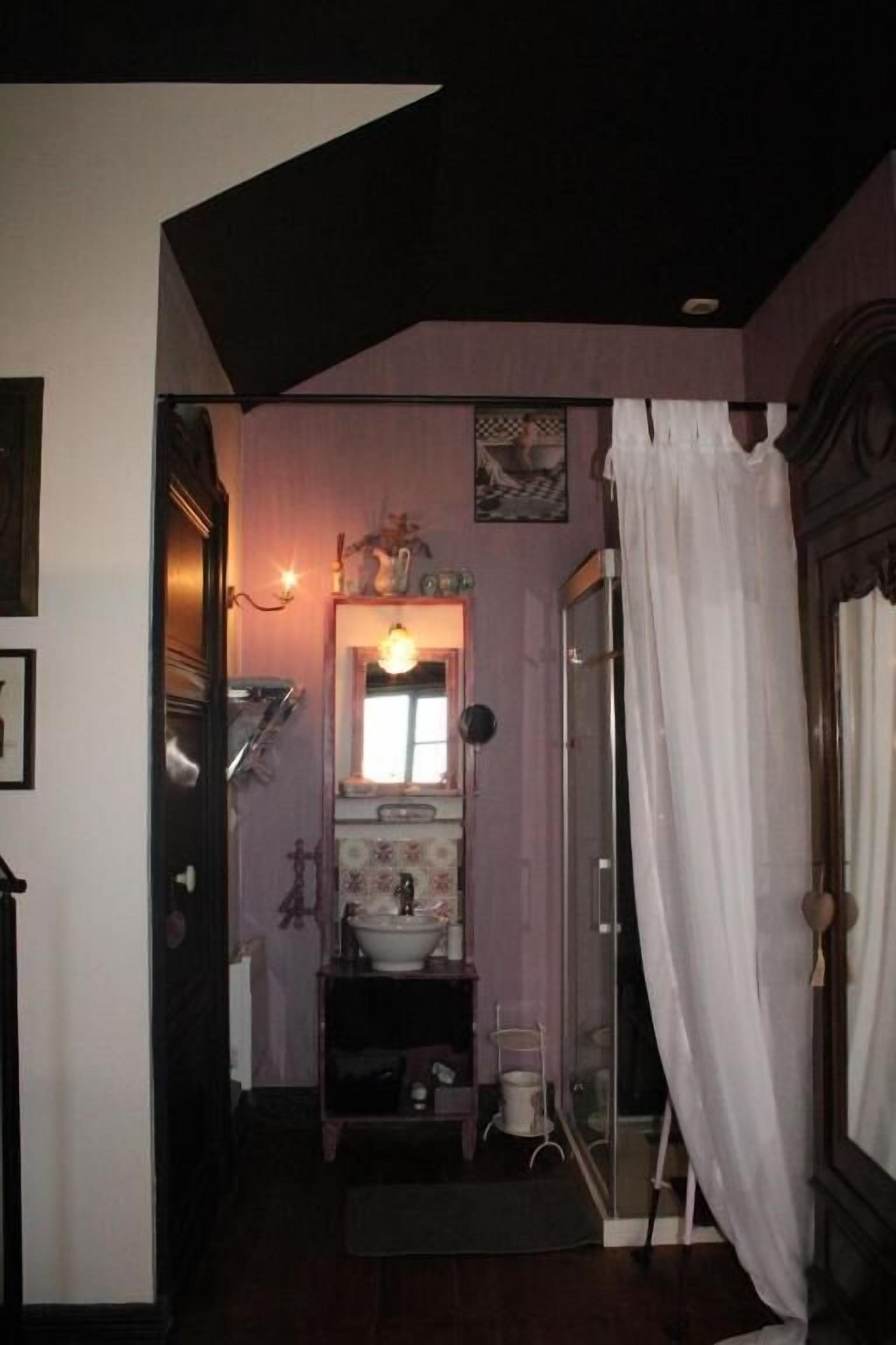 A narrow hallway leading to a bathroom with a sink, mirror, and shower area.