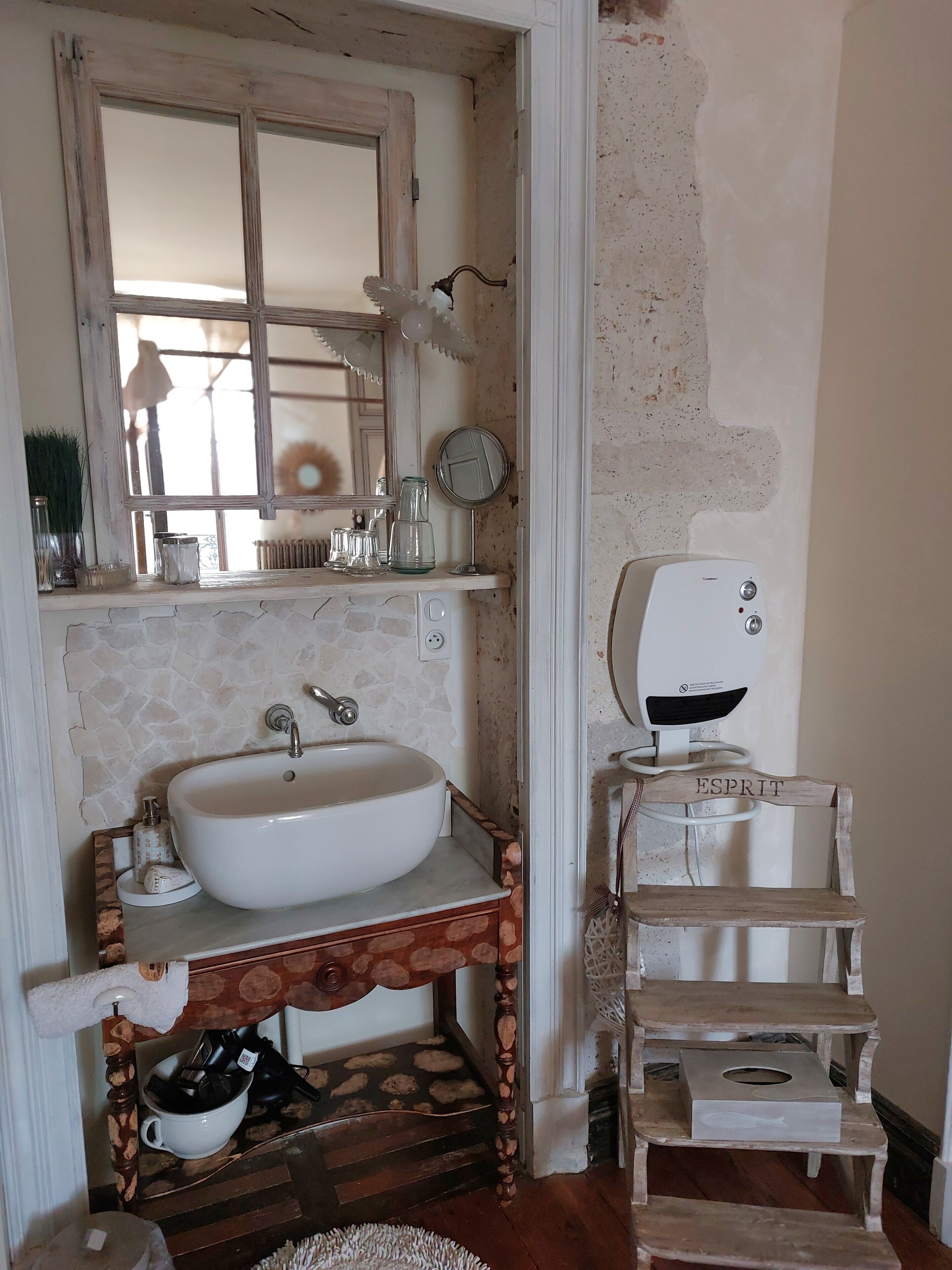 Un baño con un lavamanos blanco, un mueble de tocador de madera, un espejo y un perchero para toallas.