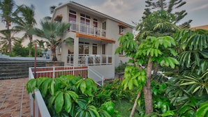 A two-story house with a balcony, surrounded by lush greenery and palm trees. - Hibiscus Villa (Grand-Baie)