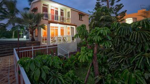 A two-story house with a balcony, surrounded by lush greenery and palm trees. - Hibiscus Villa (Grand-Baie)