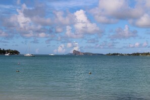 Une mer calme avec des bateaux, un ciel dégagé et une montagne lointaine.