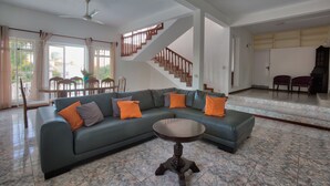 A spacious living room with a green sectional sofa, a round coffee table, and a staircase leading to another level.