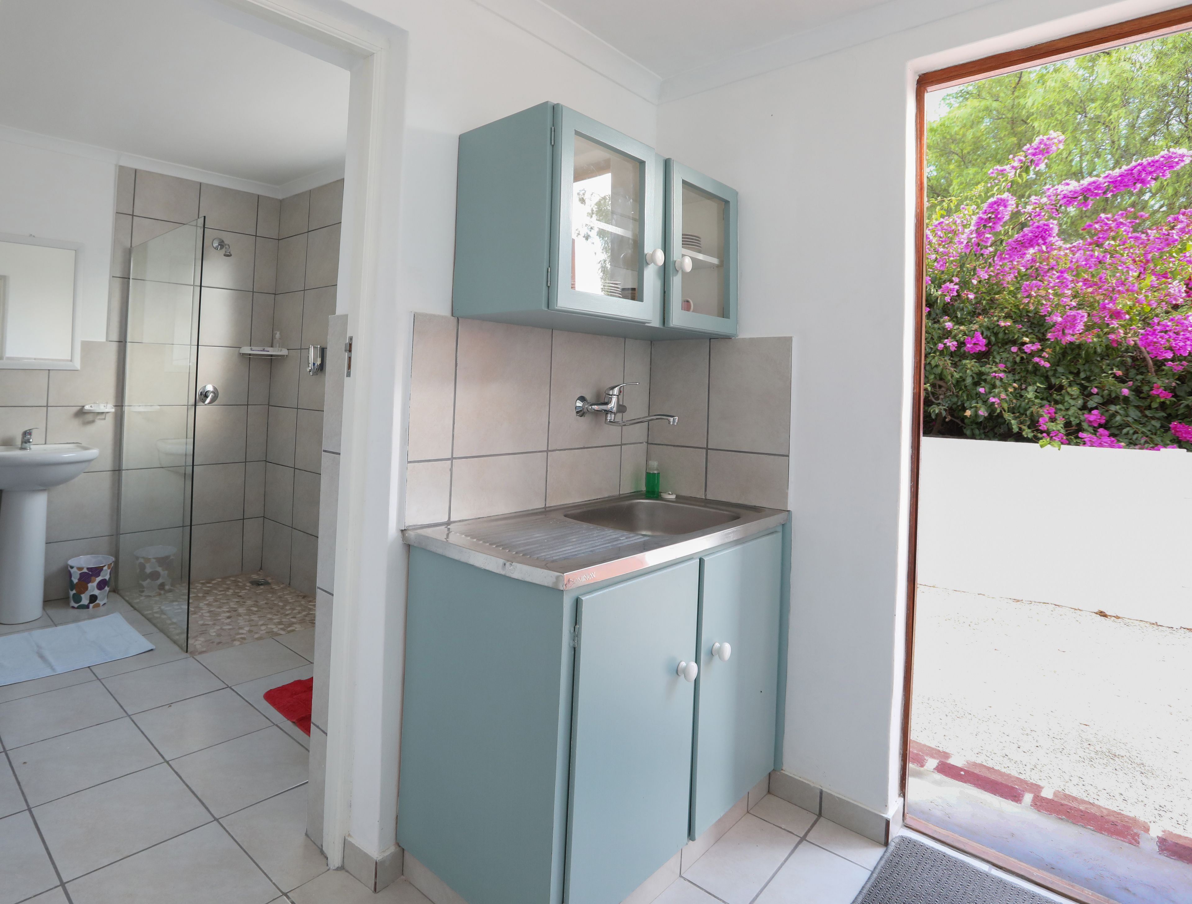 A bathroom with a shower, sink, and cabinet.