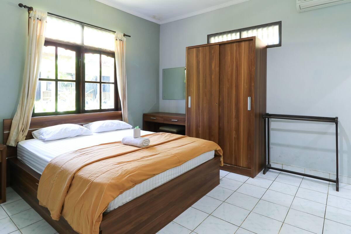 Un dormitorio con cama, armario de madera y una mesita.