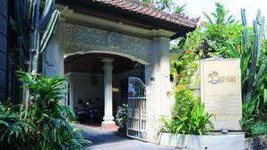 A traditional building entrance with a gate, surrounded by cacti and tropical plants. - Sari Indah Cottages (Kuta)