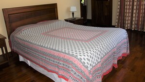 Cama bem arrumada com colcha estampada e cabeceira de madeira.