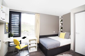 Un dormitorio moderno con una cama, un escritorio y una silla.