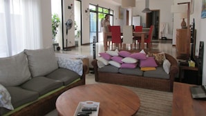 Een woonkamer met een bank, een salontafel en een eethoek met stoelen en een tafel.