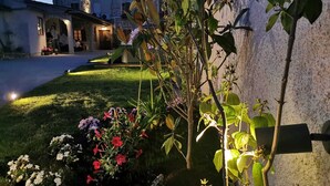 A well-maintained garden with various flowering plants and a neatly trimmed lawn in front of a house with a stone facade and a tiled roof. - Agroturizam Stelio (Marcana)
