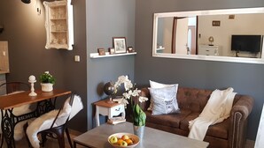 A living room with a brown sofa, a wooden table, and a dining area with a chair. - Agroturizam Stelio (Marcana)