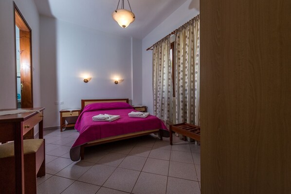 Ein Schlafzimmer mit einem Bett, Nachttischen, einem Schreibtisch und einer Pendelleuchte.