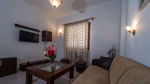 Una sala de estar con sofá, una mesa de centro, televisor y un jarrón decorativo.