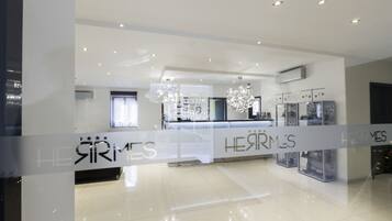 Un hall d’hôtel moderne avec une paroi en verre sur laquelle est inscrit le nom « HEARMES ».