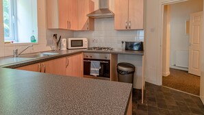 A modern kitchen with granite countertops, stainless steel appliances, and wooden cabinets. - Perfect Flat in Central Edinburgh (Edinburgh)