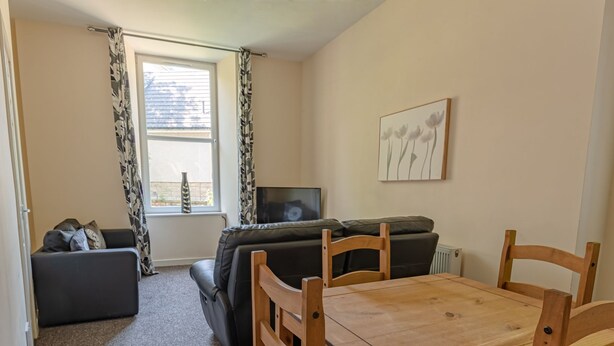 A living room with a sofa, a wooden dining table, and a TV. - Perfect Flat in Central Edinburgh (Edinburgh)
