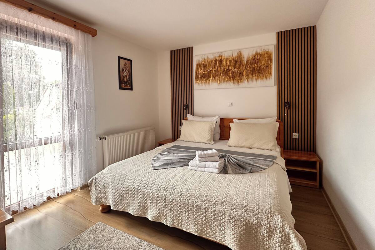 Un dormitorio con una cama grande, un radiador, una ventana con cortinas y una obra de arte colgada en la pared.