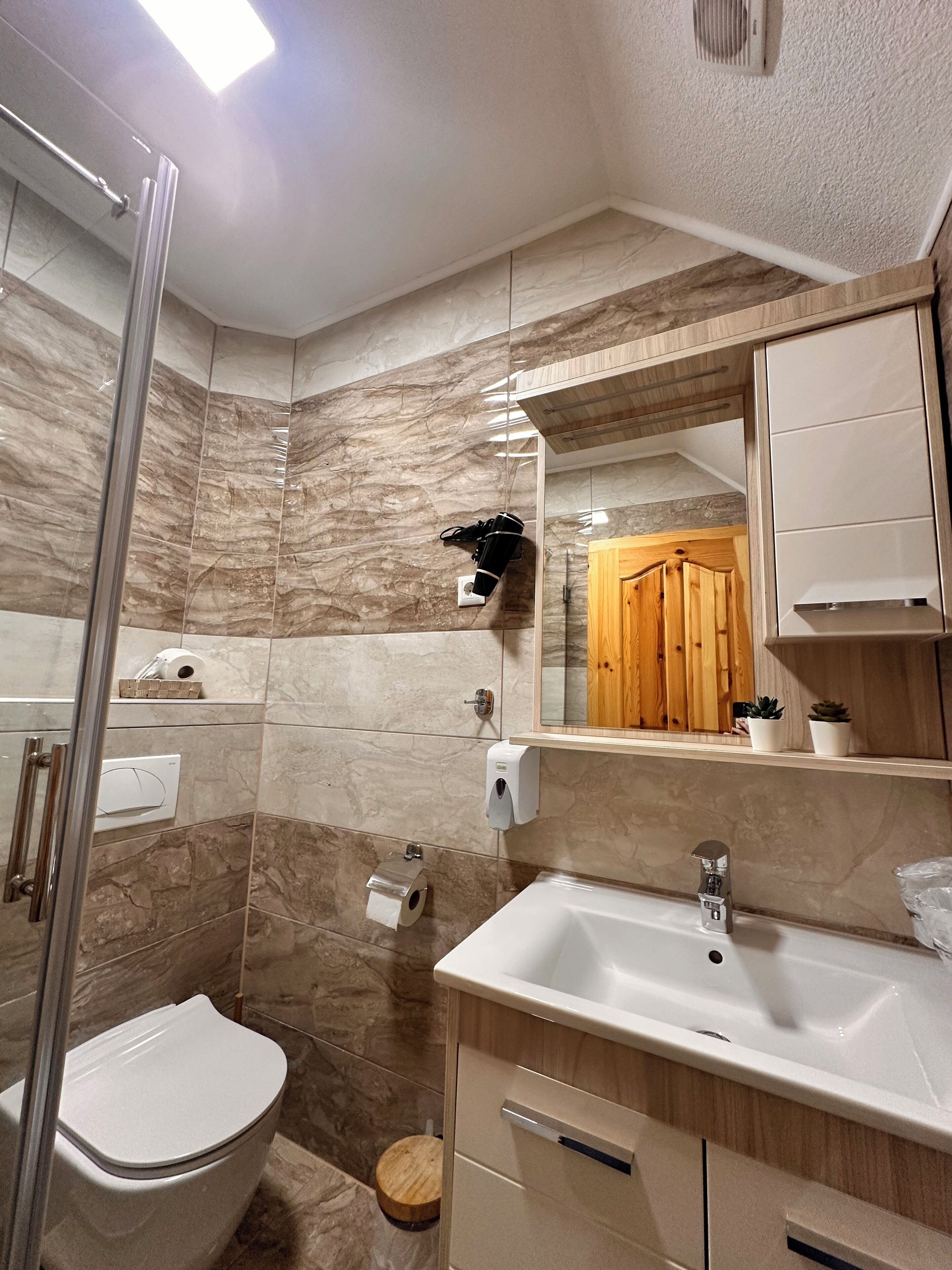 A bathroom with a toilet, sink, mirror, and shower.