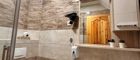 A bathroom with a toilet, sink, mirror, and shower.