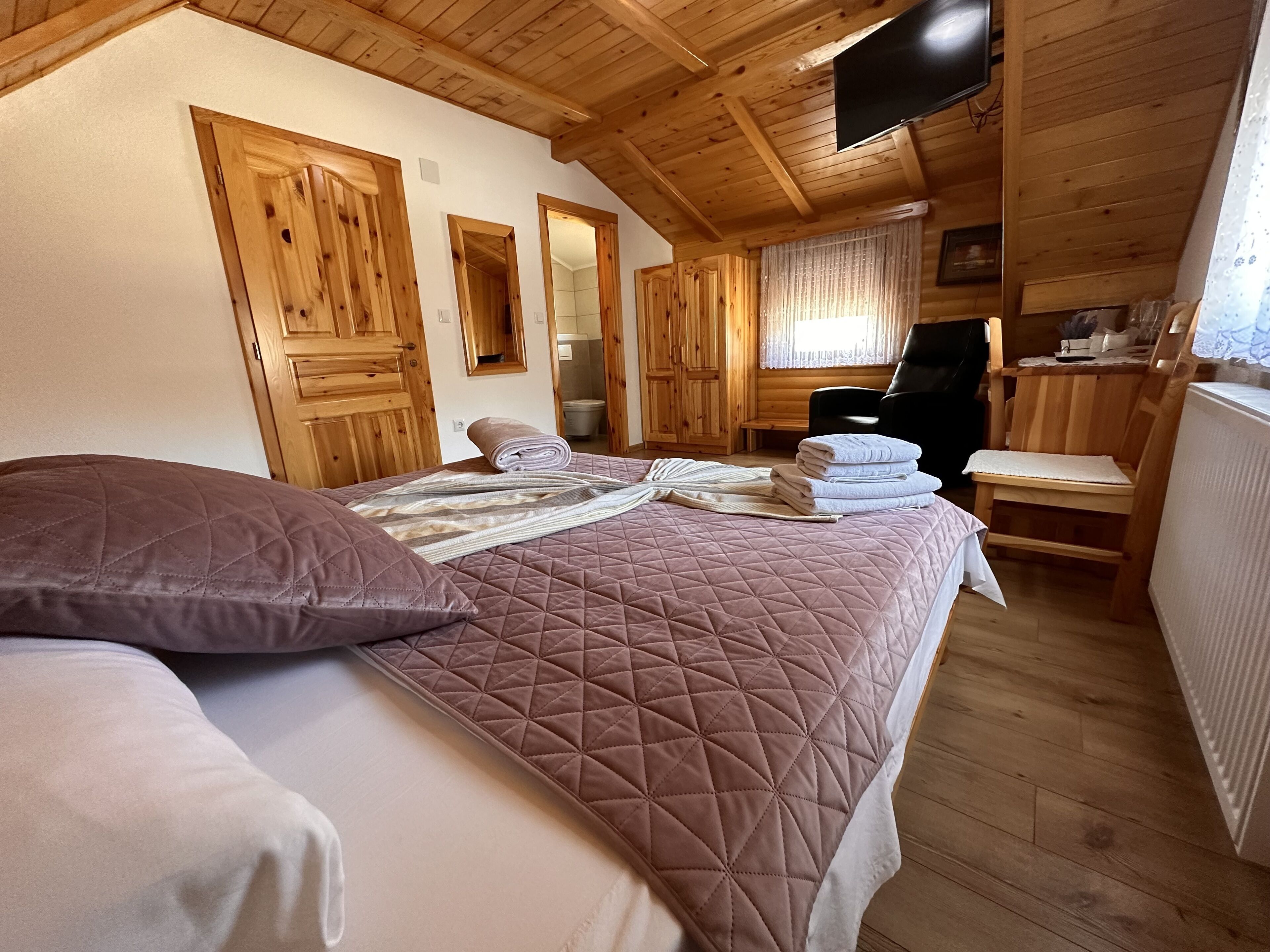 Una habitación acogedora con una cama, una silla y un televisor.