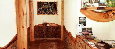 Un pasillo con paredes de madera y una chimenea de piedra. Se observa un banco de madera y una alfombra en el suelo.
