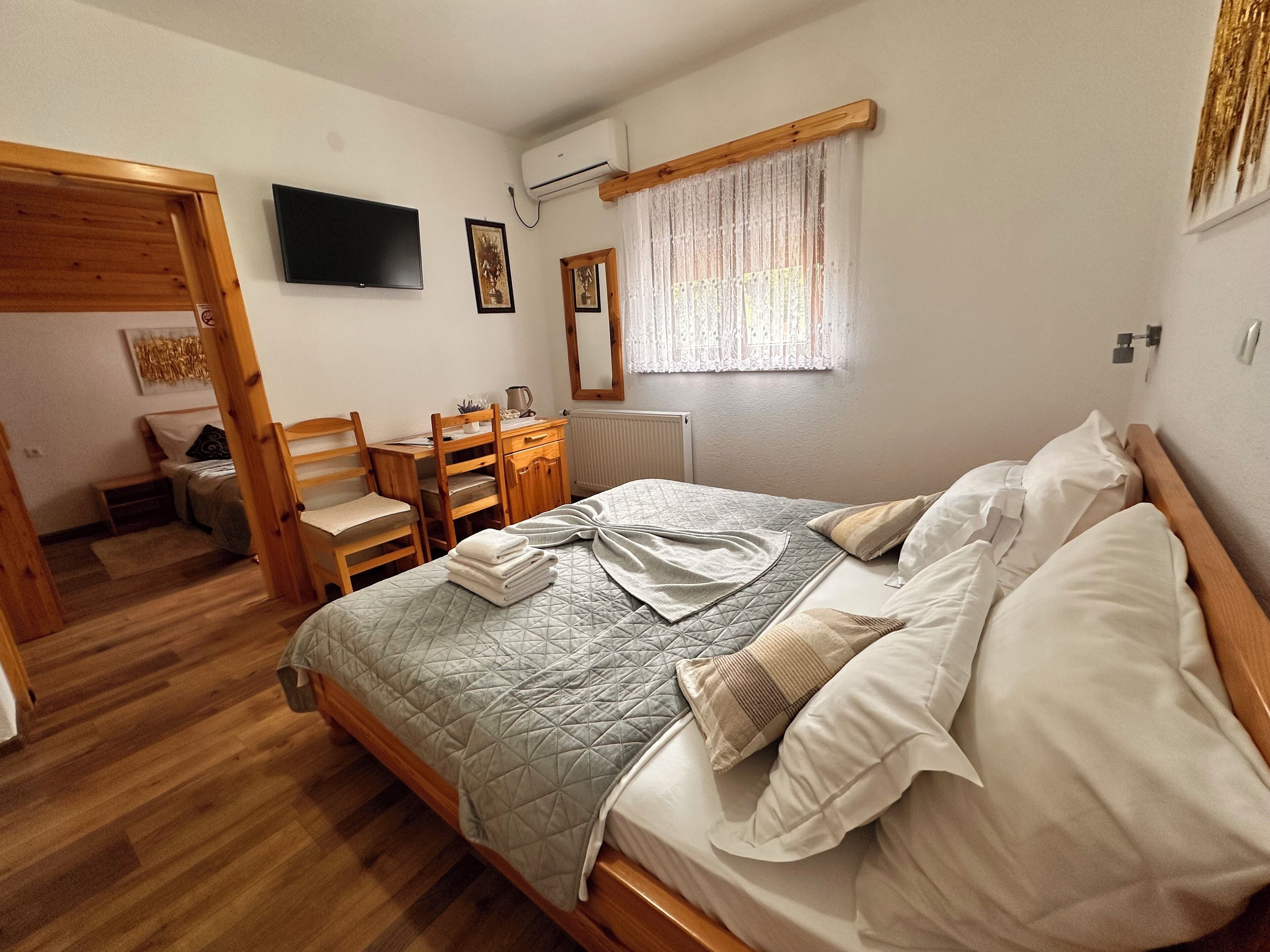 A bedroom with a bed, wooden furniture, a television, and a window with curtains.