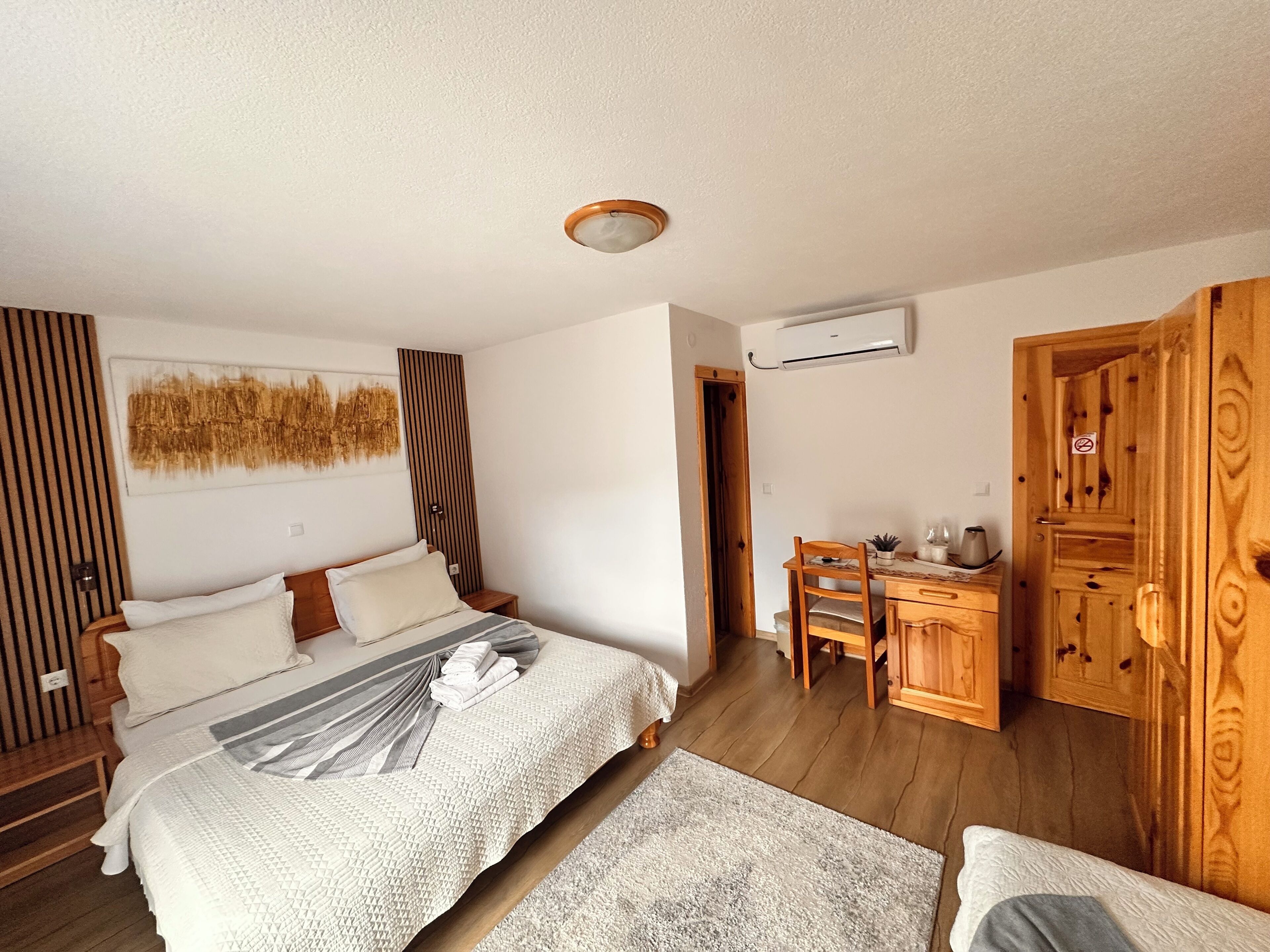 A bedroom with a bed, bedside table, and a desk with a chair.