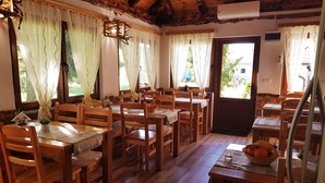 A dining area with wooden tables and chairs, a chandelier, and a view of the outdoors. - Plitvice Green Valley (Plitvicka Jezera)