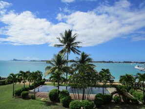 Un resort con piscina, palmeras y vistas al océano.