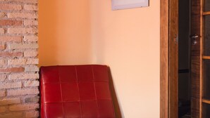 A red leather chair in a corner with a brick wall and wooden floor. - A Corona del Reino (Ejea De Los Caballeros)