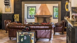 Un salon chaleureux avec des meubles en cuir, une cheminée et des bagages anciens.