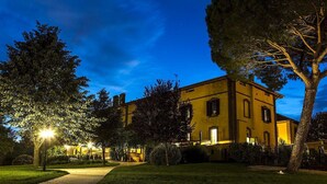 Un bâtiment historique à la façade jaune, entouré d’arbres et bordé d’un chemin bien éclairé.