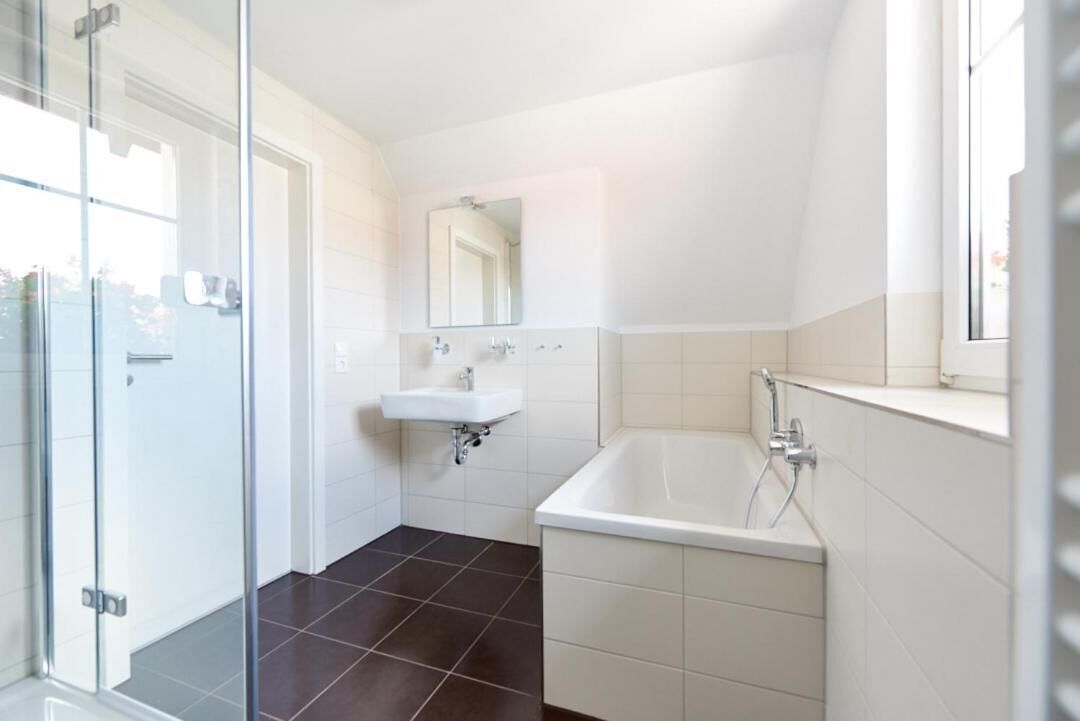 A modern bathroom with a glass shower enclosure, a white sink, and a bathtub.