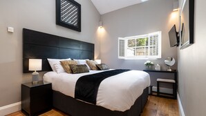 Un dormitorio moderno con una cama grande, mesitas de noche, un escritorio y una ventana con persianas.