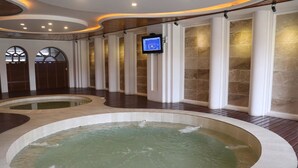 Uma área de spa com duas banheiras de hidromassagem e uma televisão fixada na parede.