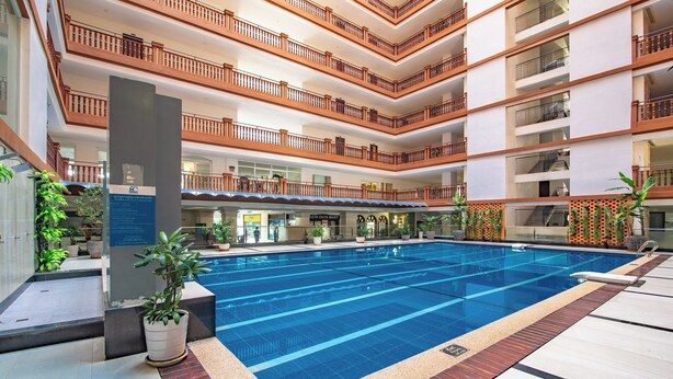 Piscina interna em vários níveis, com grades de madeira e plantas em vasos.