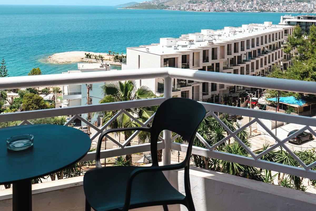 Un balcón con vistas al mar, una silla y una mesa.
