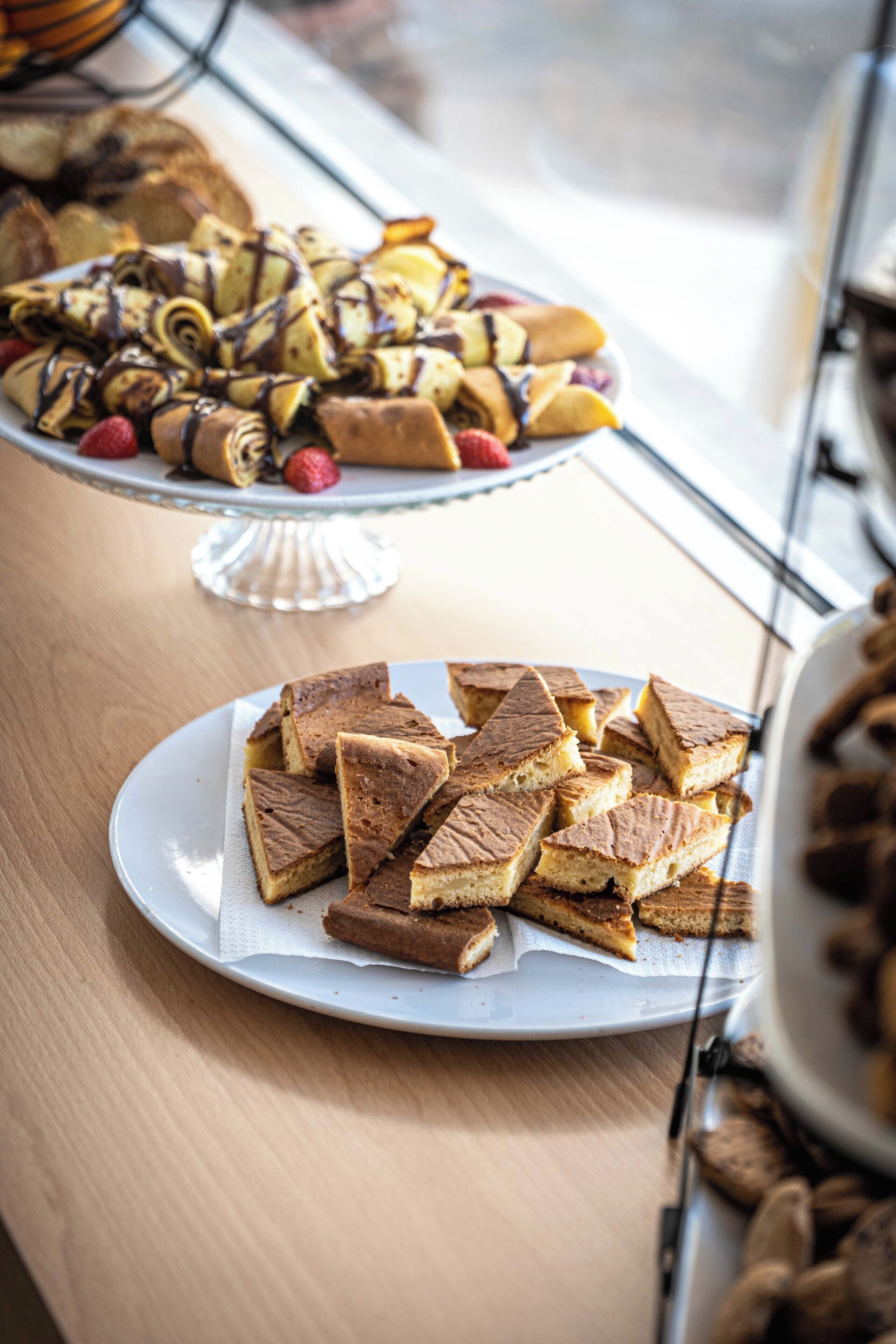 A table with a plate of brownies and a plate of pastries.