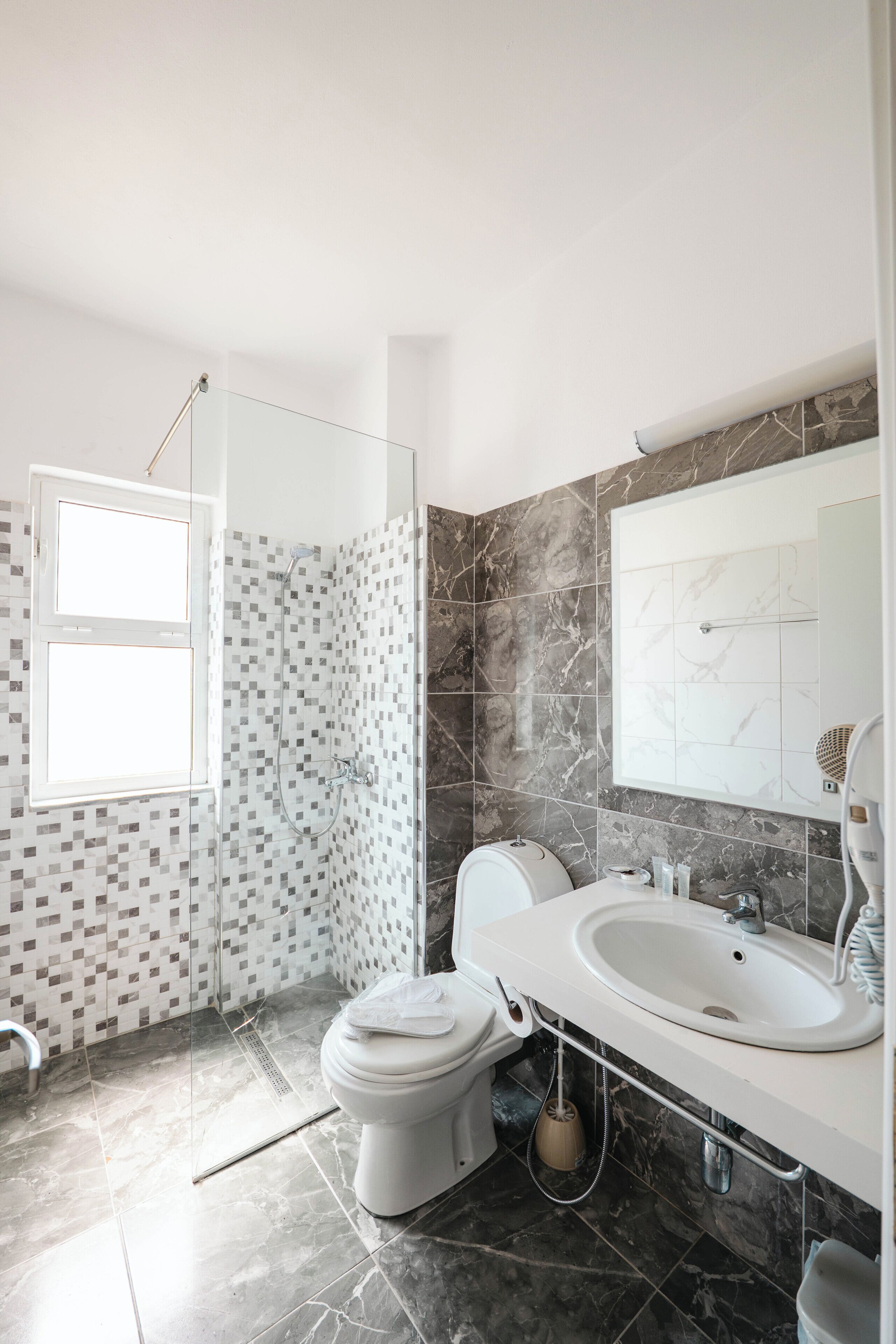 A modern bathroom with a shower, toilet, sink, and a large mirror.