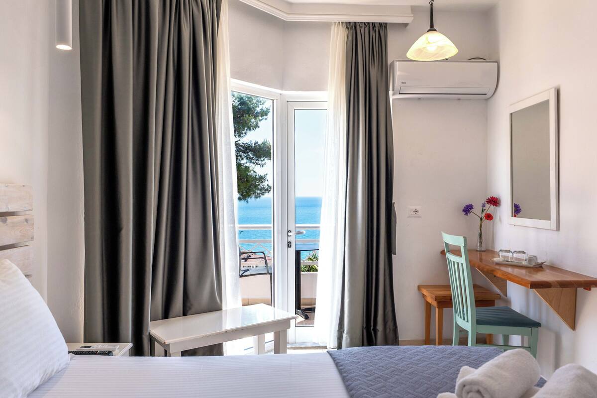 Habitación de hotel con cama, escritorio, silla y vista al mar.