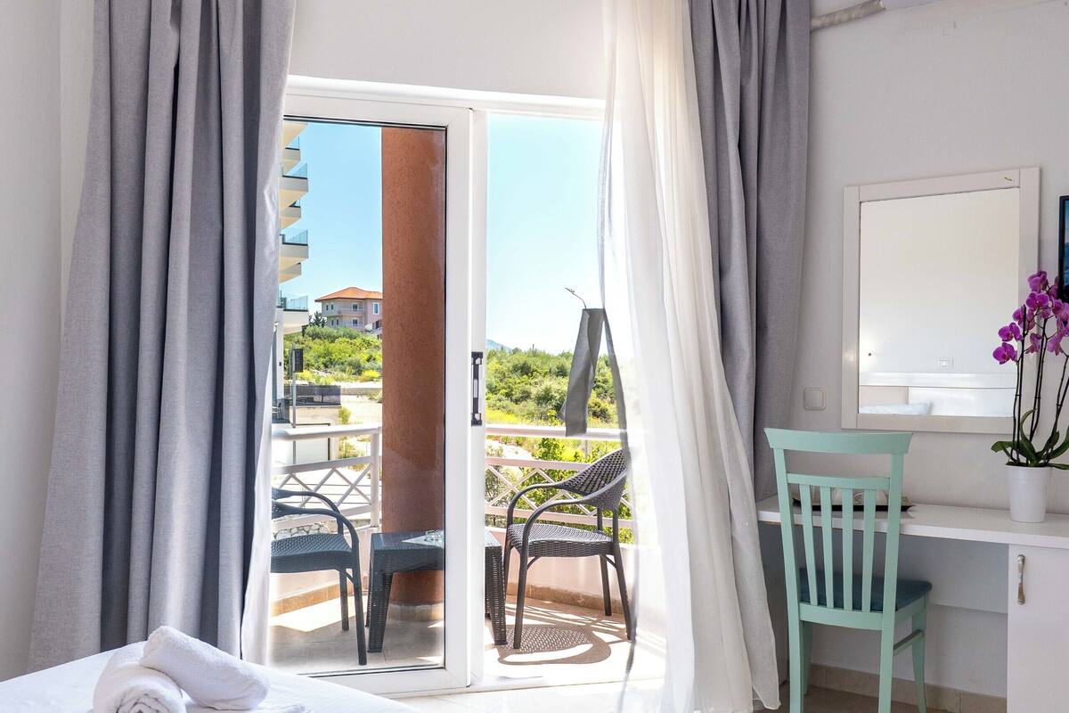 Una habitación de hotel con una cama, un escritorio, una silla y vistas al exterior.