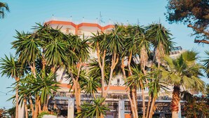 Edifici amb diversos balcons, envoltat de palmeres.
