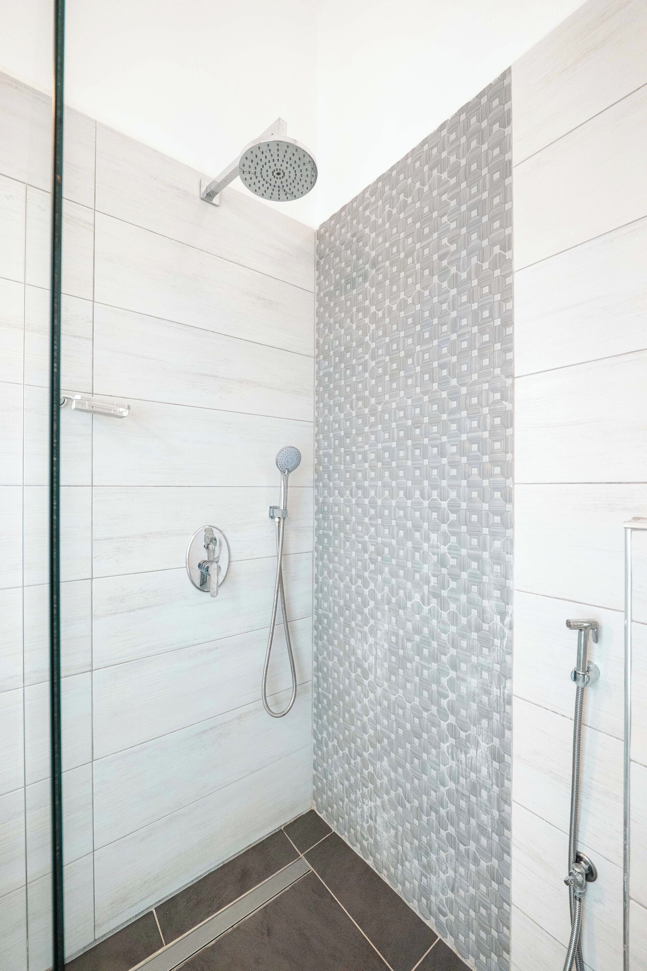 A shower with a handheld showerhead and a wall-mounted faucet.